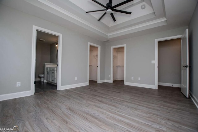 328 Brookstone Dr, Carrollton, GA 30116 - unfurnished bedroom with a tray ceiling, wood finished floors, a walk in closet, and ensuite bath