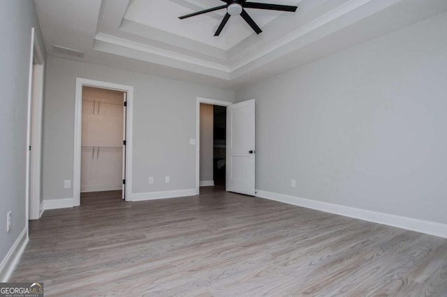 328 Brookstone Dr, Carrollton, GA 30116 - unfurnished bedroom with a tray ceiling, wood finished floors, a walk in closet, a ceiling fan, and a closet