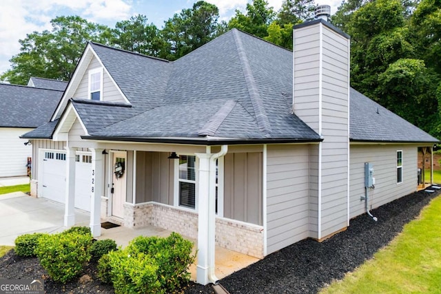 328 Brookstone Dr, Carrollton, GA 30116 - view of front of home with board and batten siding, roof with shingles, a chimney, a porch, and driveway