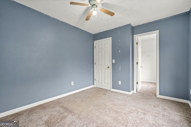 4753 Klondike Cv, Lithonia, GA 30038 - unfurnished bedroom with a textured ceiling, carpet, a walk in closet, a closet, and a ceiling fan