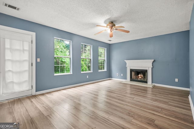 4753 Klondike Cv, Lithonia, GA 30038 - unfurnished living room featuring ceiling fan, wood finished floors, a textured ceiling, and a warm lit fireplace