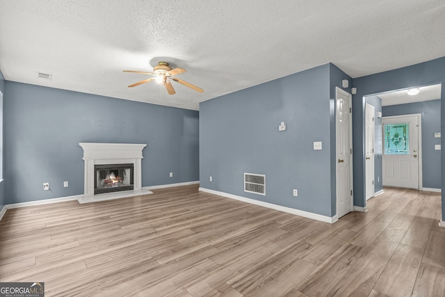 4753 Klondike Cv, Lithonia, GA 30038 - unfurnished living room featuring a ceiling fan, a textured ceiling, light wood finished floors, and a lit fireplace