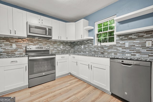 4753 Klondike Cv, Lithonia, GA 30038 - kitchen with stainless steel appliances, open shelves, stone counters, light wood-style floors, and a textured ceiling