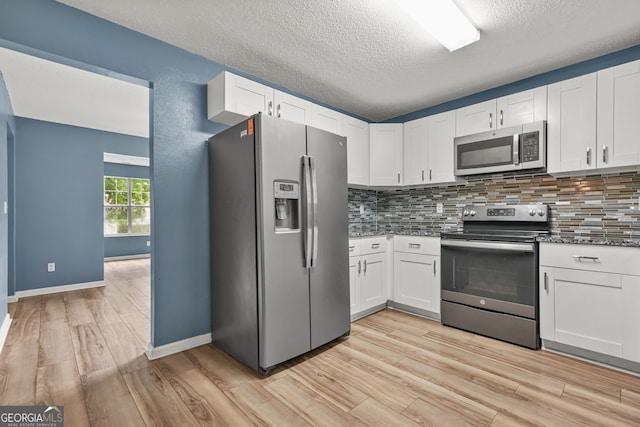 4753 Klondike Cv, Lithonia, GA 30038 - kitchen featuring appliances with stainless steel finishes, light wood-style flooring, decorative backsplash, white cabinets, and a textured ceiling