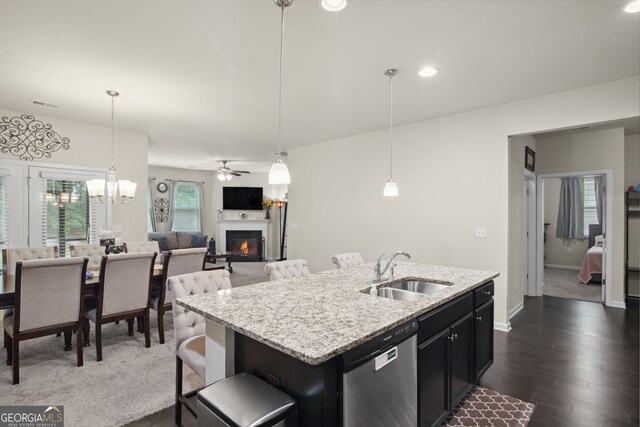 115 Court Xing, Locust Grove, GA 30248 - kitchen featuring stainless steel dishwasher, a glass covered fireplace, a kitchen island with sink, dark wood-type flooring, and decorative light fixtures