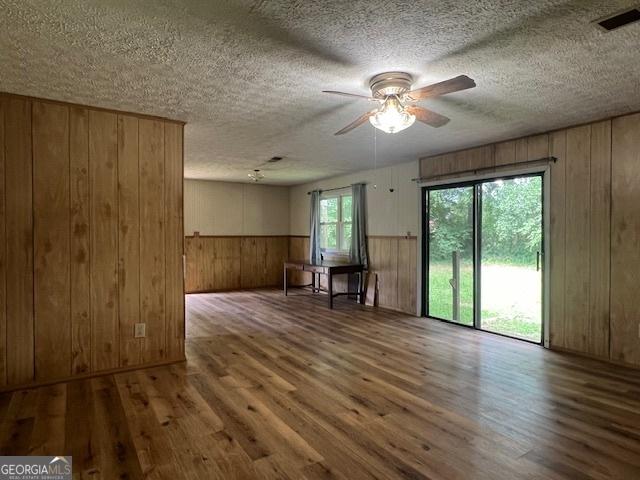 1041 Sandy Ridge Rd, Mcdonough, GA 30252 - empty room featuring wood walls, wood finished floors, ceiling fan, a textured ceiling, and a wainscoted wall