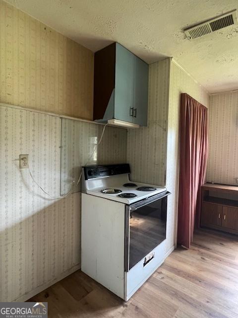 1041 Sandy Ridge Rd, Mcdonough, GA 30252 - kitchen with white electric stove, wallpapered walls, light wood-type flooring, and a textured ceiling