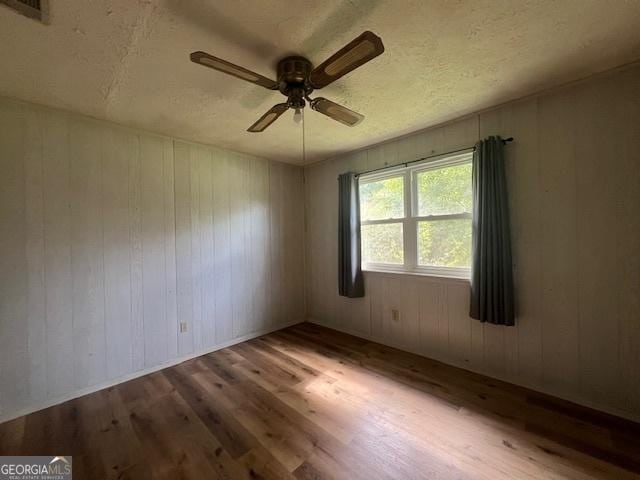 1041 Sandy Ridge Rd, Mcdonough, GA 30252 - spare room with wood finished floors, a ceiling fan, wooden walls, and a textured ceiling