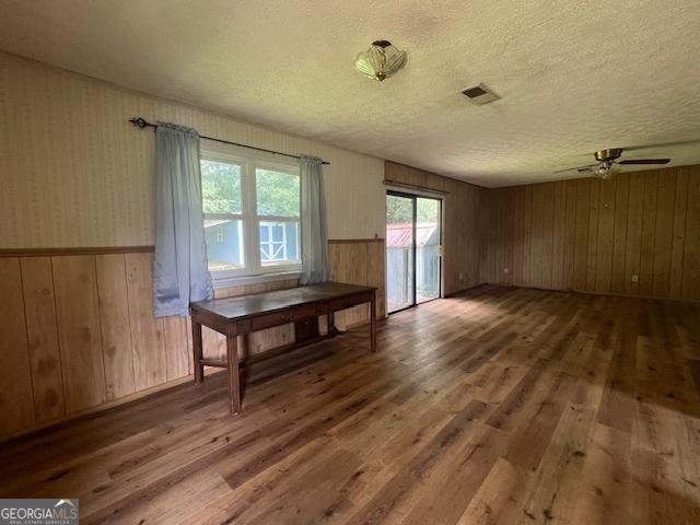 1041 Sandy Ridge Rd, Mcdonough, GA 30252 - unfurnished dining area featuring wood finished floors, a textured ceiling, ceiling fan, wooden walls, and wainscoting