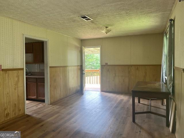 1041 Sandy Ridge Rd, Mcdonough, GA 30252 - unfurnished dining area with a textured ceiling, wood finished floors, a wainscoted wall, wood walls, and wallpapered walls