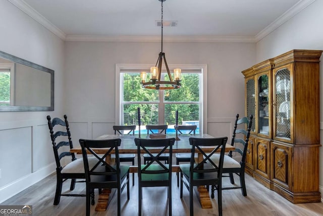 1111 Mcleods Estates Dr, Monroe, GA 30655 - dining space featuring light wood-style flooring, a chandelier, ornamental molding, and a decorative wall