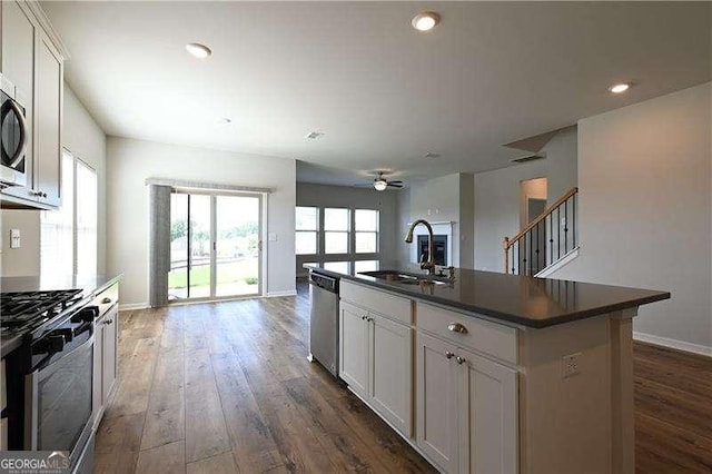 1057 Towne Mill Xing, Canton, GA 30114 - kitchen featuring appliances with stainless steel finishes, dark countertops, open floor plan, ceiling fan, and dark wood-style floors