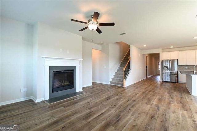 1057 Towne Mill Xing, Canton, GA 30114 - unfurnished living room featuring a ceiling fan, wood finished floors, a fireplace with flush hearth, stairs, and recessed lighting