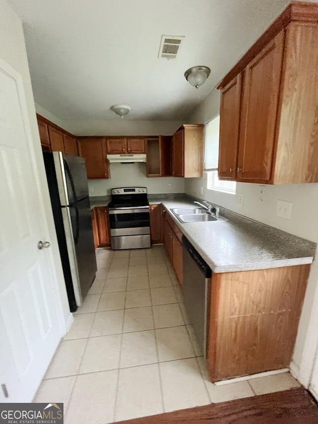 1042 Wheel House Ln Unit C, Monroe, GA 30655 - kitchen with stainless steel appliances, under cabinet range hood, light tile patterned floors, and brown cabinetry