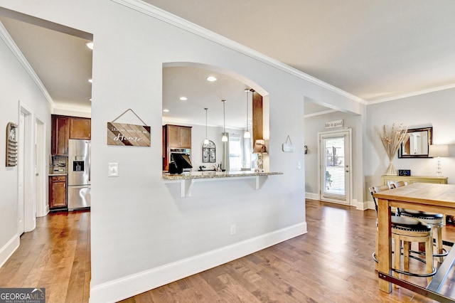 2325 Lake Cove Ct, Buford, GA 30519 - kitchen featuring stainless steel fridge with ice dispenser, arched walkways, crown molding, light wood-style floors, and a breakfast bar