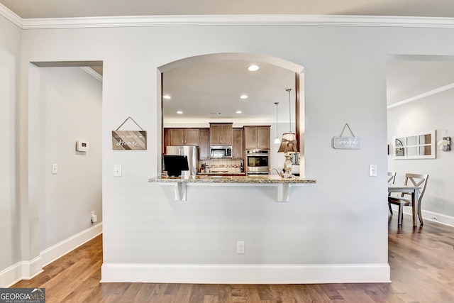 2325 Lake Cove Ct, Buford, GA 30519 - kitchen with appliances with stainless steel finishes, arched walkways, ornamental molding, wood finished floors, and a kitchen breakfast bar