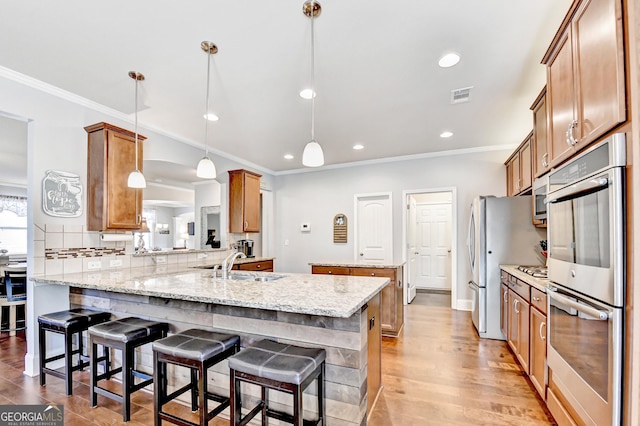 2325 Lake Cove Ct, Buford, GA 30519 - kitchen featuring stainless steel appliances, a peninsula, brown cabinetry, ornamental molding, and a kitchen breakfast bar