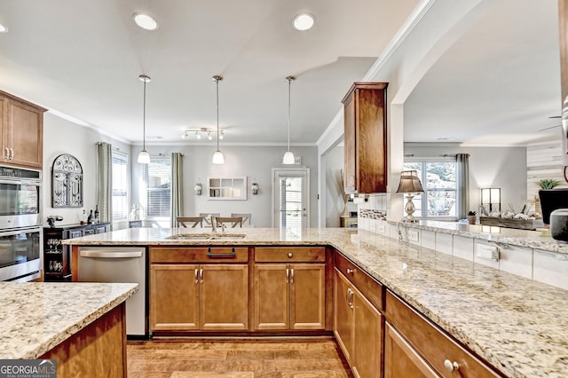 2325 Lake Cove Ct, Buford, GA 30519 - kitchen with appliances with stainless steel finishes, light stone countertops, ornamental molding, a peninsula, and light wood-type flooring