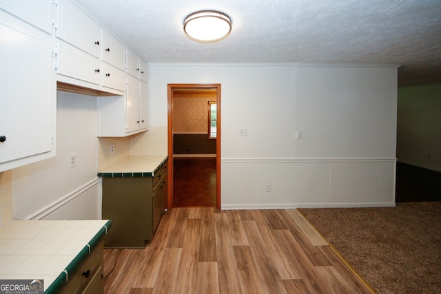 2202 Springdale Dr, Snellville, GA 30078 - kitchen featuring tile countertops, light wood-style flooring, white cabinetry, tasteful backsplash, and a textured ceiling