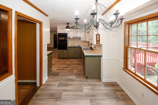 2202 Springdale Dr, Snellville, GA 30078 - kitchen featuring a chandelier, black appliances, light wood finished floors, under cabinet range hood, and backsplash