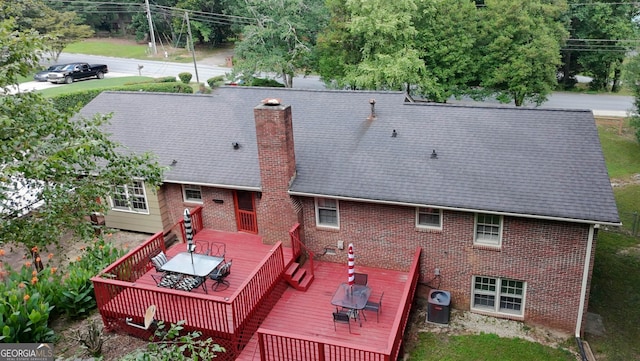 2202 Springdale Dr, Snellville, GA 30078 - rear view of house with outdoor dining space, a wooden deck, brick siding, and a chimney
