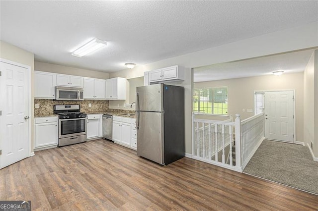 7420 Bristol, Douglasville, GA 30134 - kitchen with stainless steel appliances, white cabinetry, wood finished floors, decorative backsplash, and a textured ceiling