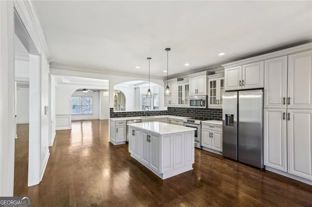 2108 Main St NW, Atlanta, GA 30318 - kitchen with appliances with stainless steel finishes, arched walkways, glass insert cabinets, a center island, and ornamental molding
