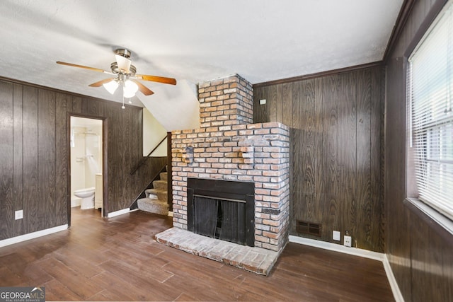 1517 Indian Forest Trl, Stone Mountain, GA 30083 - unfurnished living room with wooden walls, ceiling fan, healthy amount of natural light, stairs, and a brick fireplace
