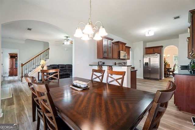 1147 Scenic Park Trl, Lawrenceville, GA 30046 - dining space with arched walkways, a ceiling fan, stairway, light wood finished floors, and a chandelier