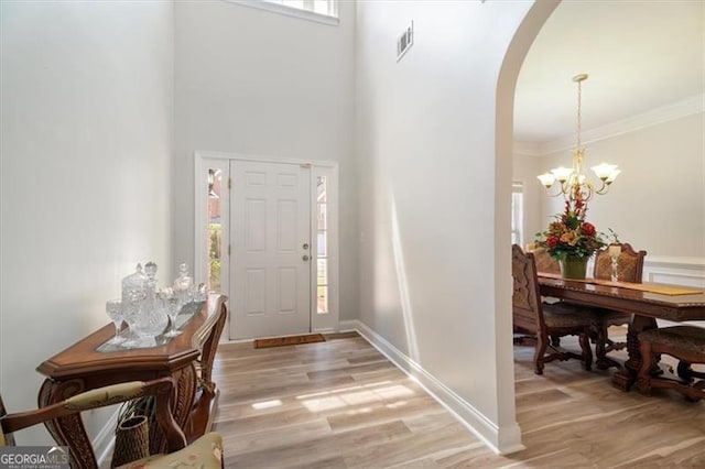 1147 Scenic Park Trl, Lawrenceville, GA 30046 - entrance foyer with arched walkways, light wood finished floors, a chandelier, a towering ceiling, and crown molding