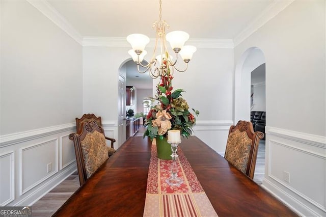 1147 Scenic Park Trl, Lawrenceville, GA 30046 - dining room featuring arched walkways, a chandelier, wood finished floors, ornamental molding, and a decorative wall