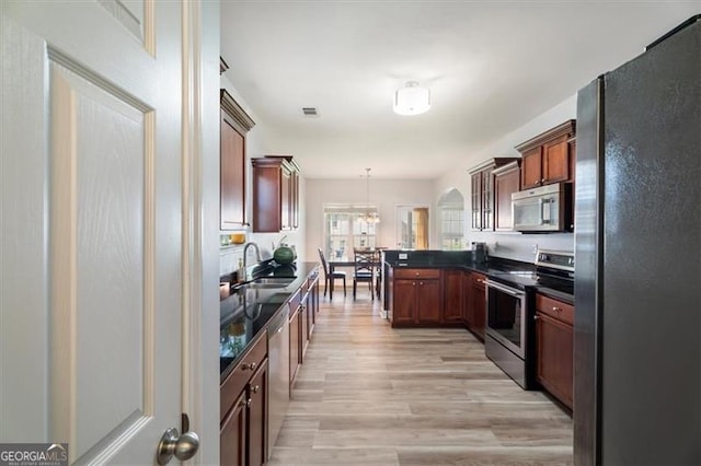 1147 Scenic Park Trl, Lawrenceville, GA 30046 - kitchen with appliances with stainless steel finishes, dark countertops, a peninsula, light wood finished floors, and pendant lighting
