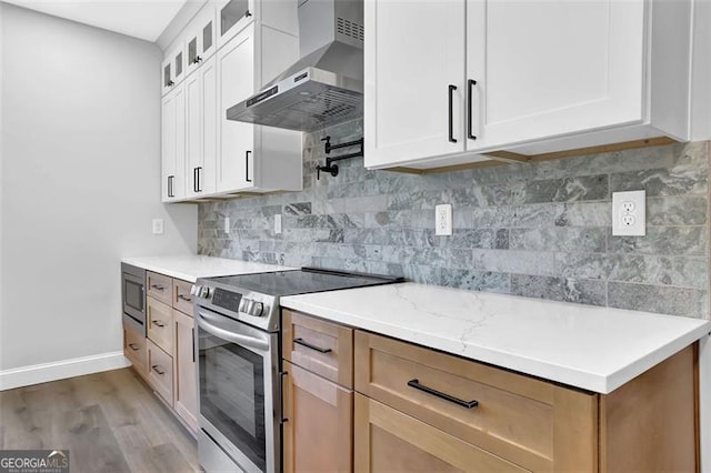 5719 Calm Vly, Flowery Branch, GA 30542 - kitchen with appliances with stainless steel finishes, wall chimney range hood, glass insert cabinets, light wood-style floors, and backsplash