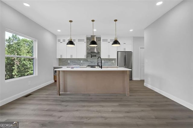 5719 Calm Vly, Flowery Branch, GA 30542 - kitchen with freestanding refrigerator, wall chimney range hood, light countertops, decorative backsplash, and a center island with sink