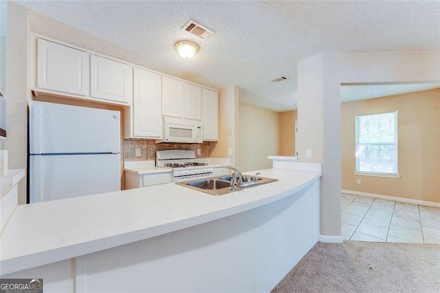 179 Glynn Addy, Stockbridge, GA 30281 - kitchen with white appliances, white cabinets, light countertops, a peninsula, and light carpet