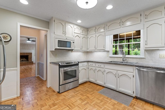 829 Bev Ct, Lawrenceville, GA 30046 - kitchen with stainless steel appliances, decorative backsplash, a textured ceiling, a fireplace, and a ceiling fan