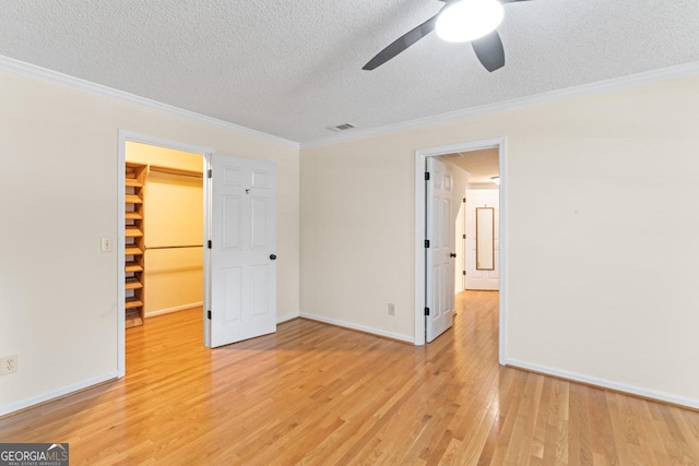 829 Bev Ct, Lawrenceville, GA 30046 - unfurnished bedroom with light wood-type flooring, a textured ceiling, a spacious closet, ornamental molding, and a closet