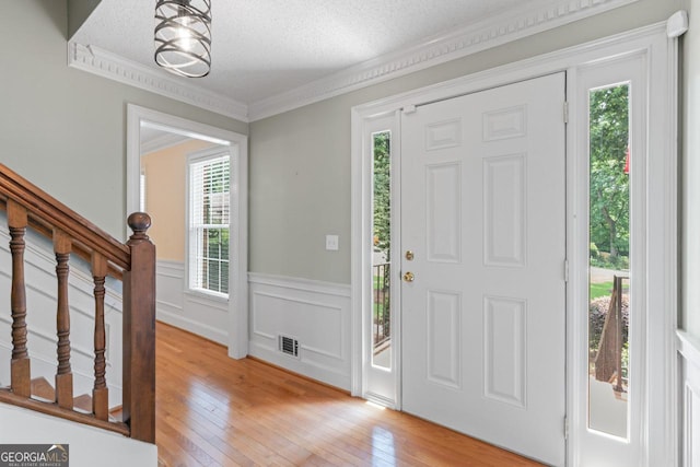 829 Bev Ct, Lawrenceville, GA 30046 - entrance foyer featuring light wood-style flooring, wainscoting, crown molding, stairs, and a textured ceiling