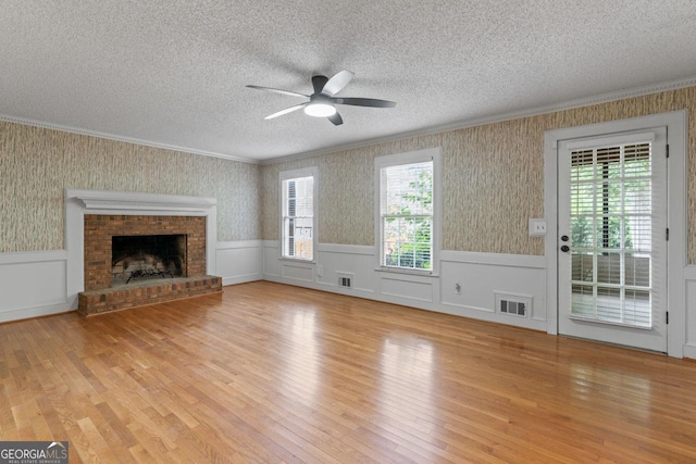 829 Bev Ct, Lawrenceville, GA 30046 - unfurnished living room with a textured ceiling, wainscoting, a ceiling fan, light wood-style flooring, and crown molding