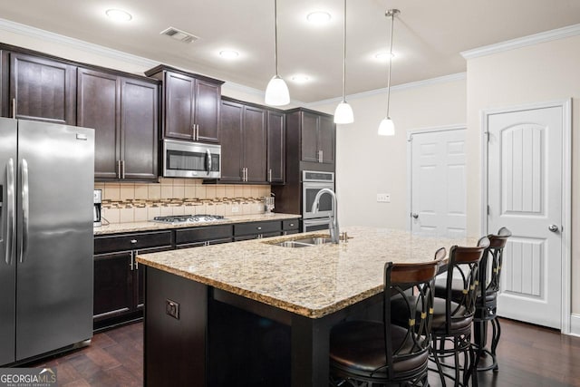 2844 Bluestone Dr SW, South Fulton, GA 30331 - kitchen featuring appliances with stainless steel finishes, ornamental molding, decorative backsplash, a kitchen breakfast bar, and a kitchen island with sink