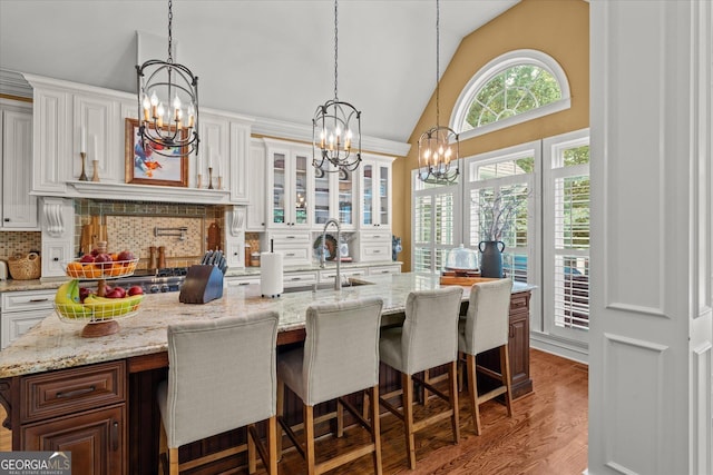 9125 Patrick Pl, Winston, GA 30187 - kitchen with a chandelier, tasteful backsplash, wood finished floors, white cabinets, and a breakfast bar area