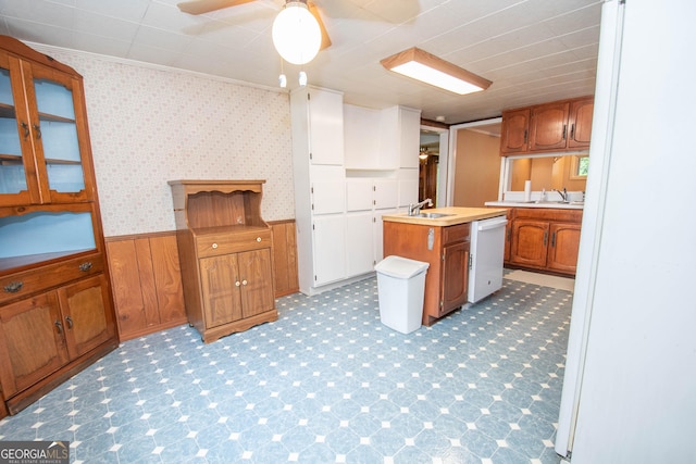 195 Hudgen Rd, Newnan, GA 30265 - kitchen with dishwasher, a wainscoted wall, brown cabinetry, light countertops, and a kitchen island with sink