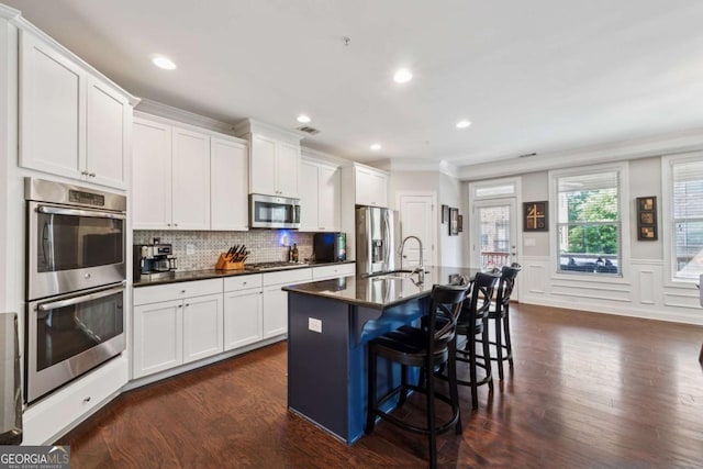 2520 Carmel Way, Alpharetta, GA 30009 - kitchen featuring appliances with stainless steel finishes, dark countertops, a kitchen breakfast bar, dark wood-type flooring, and white cabinets