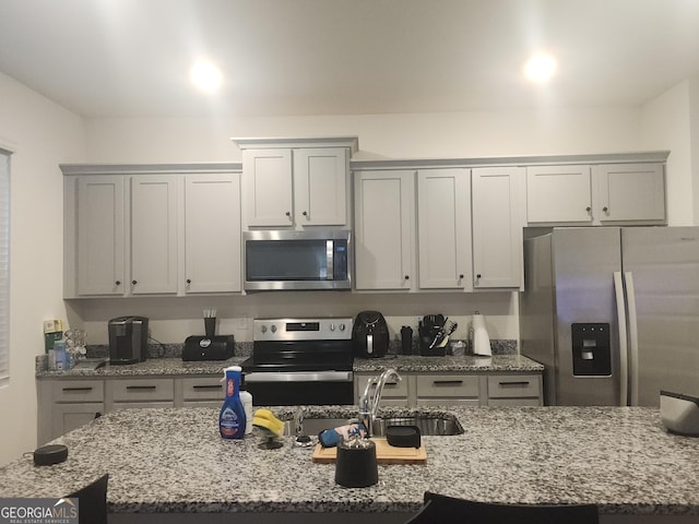 160 Grafton St, Hampton, GA 30228 - kitchen with appliances with stainless steel finishes, light stone counters, a kitchen island with sink, and gray cabinetry