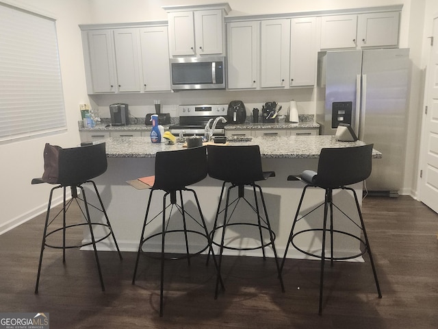 160 Grafton St, Hampton, GA 30228 - kitchen with appliances with stainless steel finishes, a kitchen island with sink, dark wood finished floors, and light stone countertops