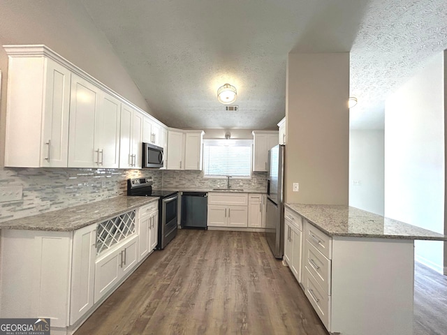 35 Belmont Way, Covington, GA 30016 - kitchen featuring stainless steel appliances, a textured ceiling, backsplash, a peninsula, and dark wood-style floors
