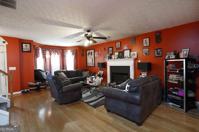 860 Sweet Mill Ln, Lawrenceville, GA 30045 - living room with light wood-style floors, a glass covered fireplace, ceiling fan, a textured ceiling, and stairs