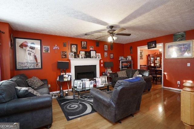 860 Sweet Mill Ln, Lawrenceville, GA 30045 - living area with wood finished floors, a ceiling fan, a textured ceiling, and a fireplace