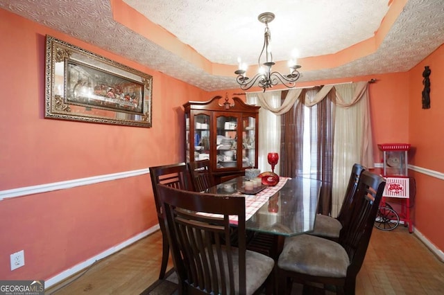 860 Sweet Mill Ln, Lawrenceville, GA 30045 - dining area with a chandelier, a textured ceiling, a raised ceiling, and wood finished floors