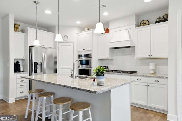 5744 Cypress Bluff Ln, Hoschton, GA 30548 - kitchen featuring appliances with stainless steel finishes, light wood finished floors, a breakfast bar area, white cabinets, and decorative backsplash